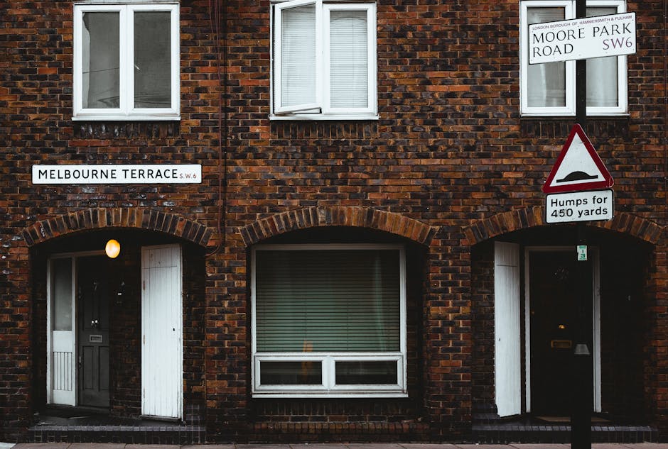 The image shows a brick residential building on Melbourne Terrace in London, featuring two ground-floor entrances with white doors set beneath brick archways. Above the doors are small, evenly spaced